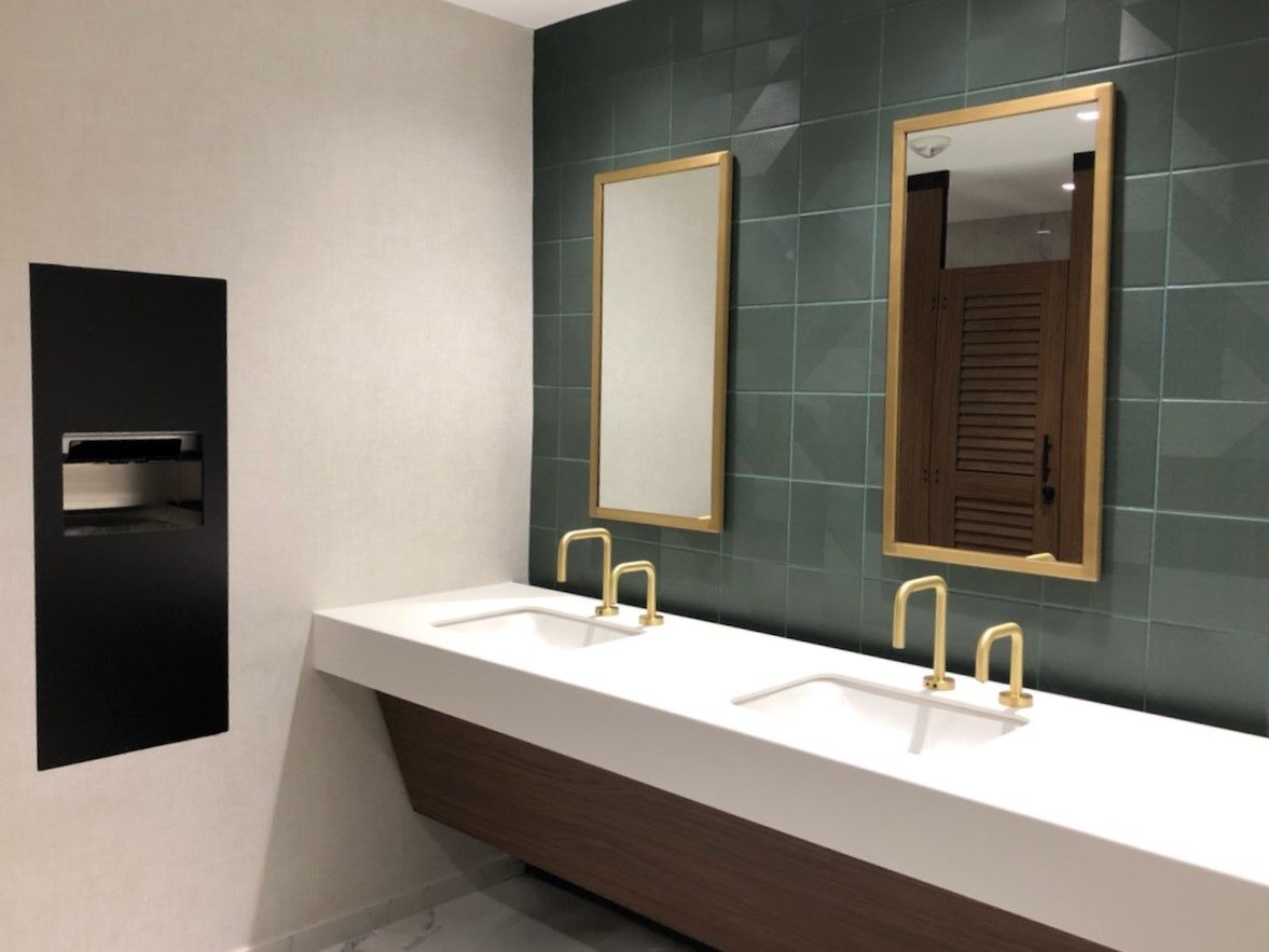 Louvered walnut partition doors with black hardware and brass mirrors