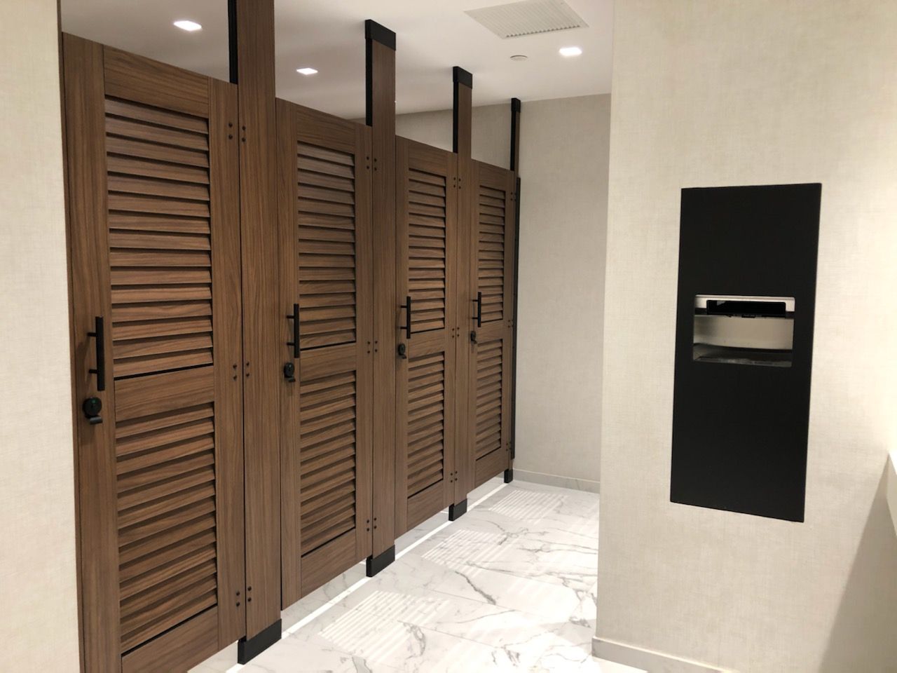 Floor-to-ceiling phenolic partitions with louvered walnut doors at 277 S. Washington, Alexandria VA