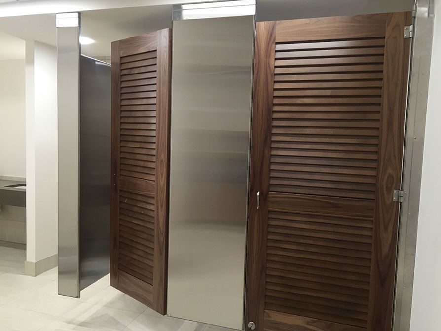 Stainless steel ceiling-hung partitions with louvered wood veneer doors at Colonial Place