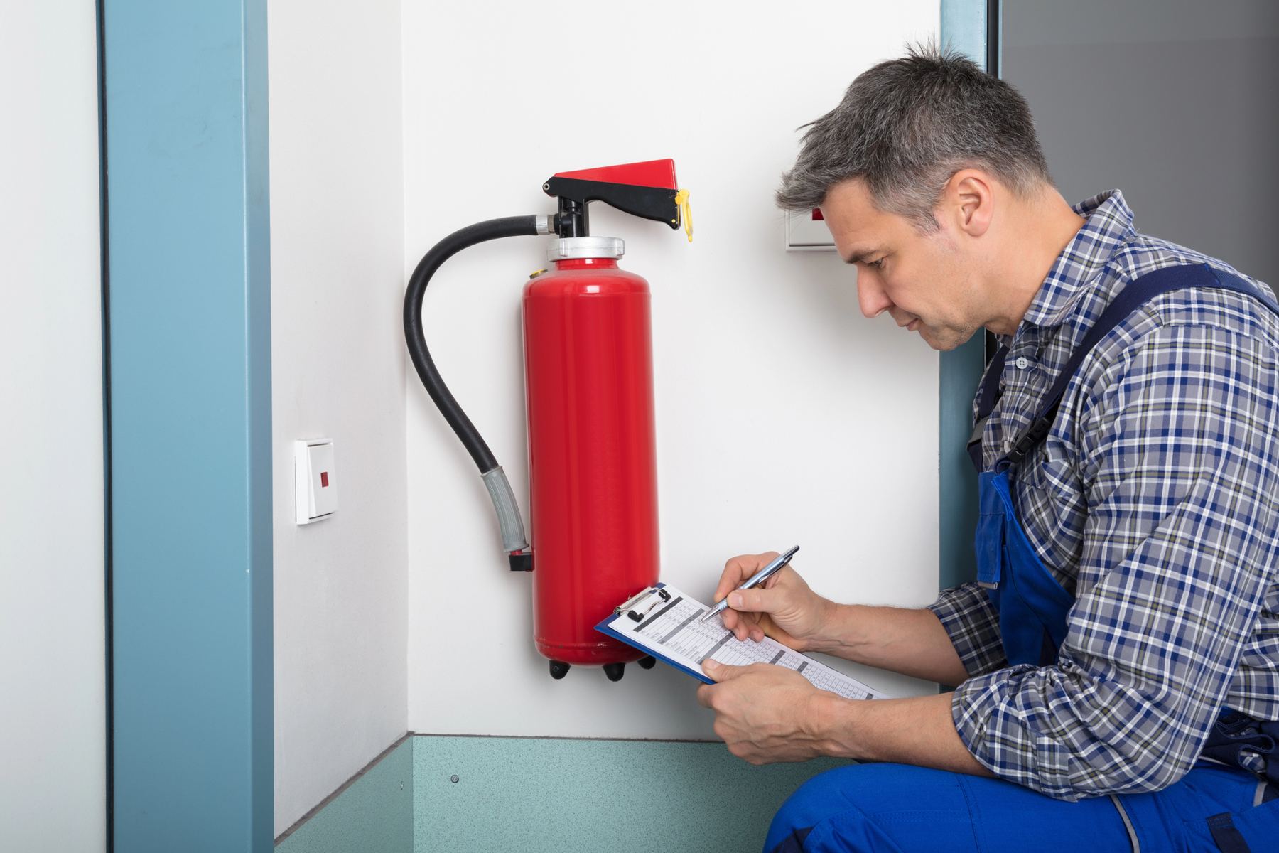 Technician inspecting a wall-mounted fire extinguisher