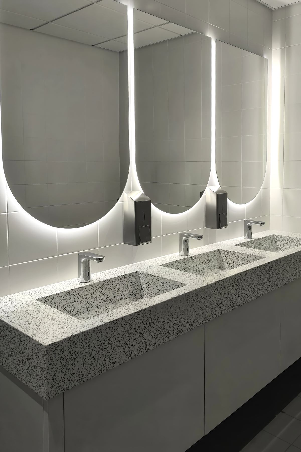 Contemporary washroom with backlit mirrors and integrated sinks